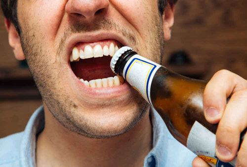Dùng răng cạy mở nắp chai cũng là nguyên nhân khiến răng bị lung lay
