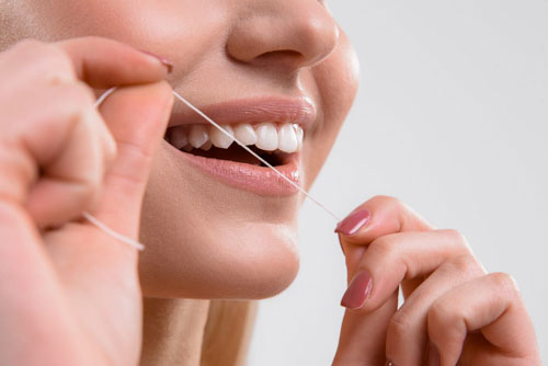 Sử dụng chỉ nha khoa loại bỏ mảng bám và thức ăn dính giắt trong kẽ răng
